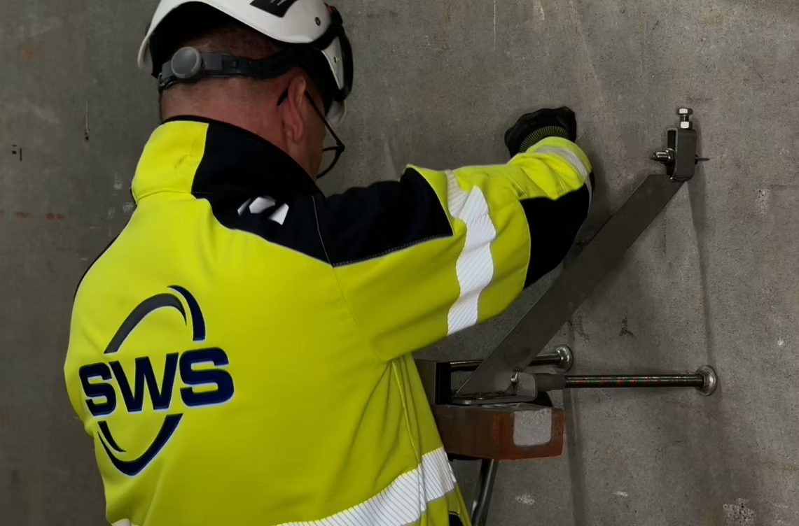 SWS-medarbejder monterer et vægbeslag på en betonvæg